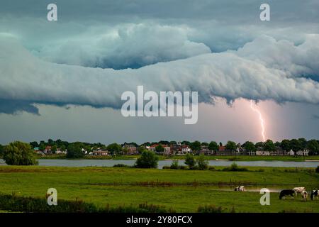 Dramatisch aussehender Himmel, als sich eine Regalwolke eines schweren Gewitters nähert, während ein Blitz einschlägt Stockfoto