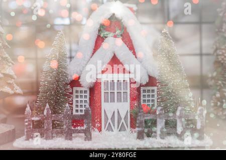 Happy New Year und Frohe Weihnachten Postkarte. Weihnachtszeit mit rotem Holzhaus, Schnee, leichtem Bokeh, Weihnachtsdorf und Dekoration. Kopierbereich Stockfoto