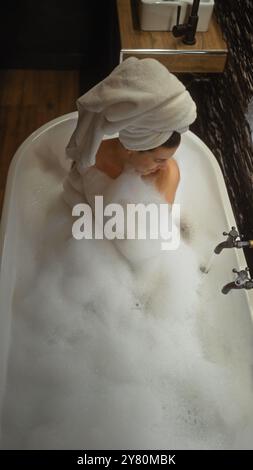 Eine junge Frau entspannt sich in einem Schaumbad zu Hause, in Ruhe und Komfort gehüllt. Stockfoto