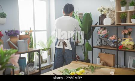 Ein junger asiatischer Mann arrangiert Pflanzen in einem pulsierenden Blumenladen. Stockfoto