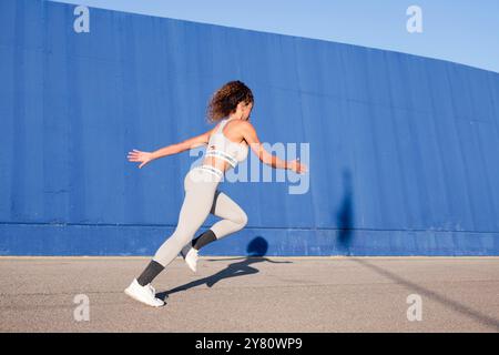 Fokussierte Läuferin sprintet auf dem Bürgersteig Stockfoto
