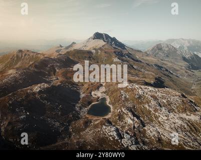 Drohnenblick auf die Savognin Berge in der Schweiz bei Sonnenuntergang mit Blick auf zerklüftete Gipfel und Täler, die in goldenes Licht getaucht sind Stockfoto