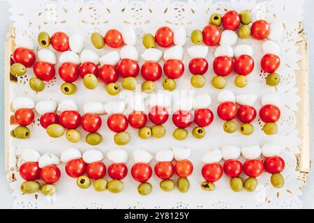 Frische Spieße mit Kirschtomaten, Mozzarella und grünen Oliven auf einem Buffettisch Stockfoto