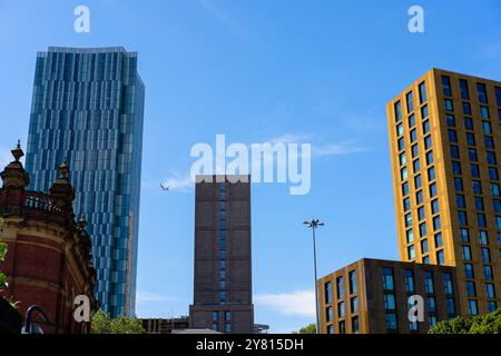 Leeds England: 2. Juni 2024: Leeds City Skyline Moderne Architektur unter klarem blauem Himmel mit einem Flugzeug, das über städtische Gebäude fliegt Stockfoto