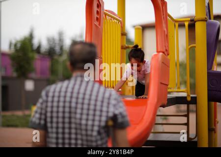 Gaziantep, Türkei. Mai 2022. Der syrische Großvater Kamal Khatib spielt mit seinem Enkel auf einem Spielplatz in Gaziantep. Kamal und sein Sohn Bashir wurden getrennt, als Kamal vor dem Krieg floh, um in Jordanien Zuflucht zu suchen. Erst zehn Jahre später, als Kamal in die Türkei reisen konnte, um seine sehr aggressive Krebsform behandeln zu lassen, kam er mit seinem Sohn wieder zusammen, der jetzt mit seiner Frau und zwei kleinen Kindern in der Türkei lebt. Das Ereignis verdeutlicht die Tragödie des Krieges in Syrien, in dem die Syrer in einem nie endenden Konflikt gefangen sind, der ihnen große Verluste, Vertreibungen und immenses Leid verursacht Stockfoto