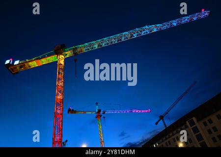München, Deutschland - 18. April 2024: Bunt beleuchtete Baukräne in der Münchner Innenstadt Stockfoto