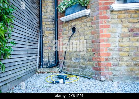 LONDON – 16. SEPTEMBER 2024: Ein elektrisches Ladekabel für Haushalte, das durch die Wand eines Wohnhauses im Südwesten Londons verlegt wurde Stockfoto