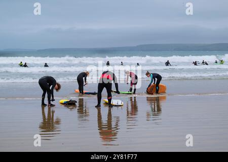 Eine Gruppe junger Surfer, die sich auf eine Surfsession am Towan Beach in Newquay in Cornwall in Großbritannien vorbereiten. Stockfoto