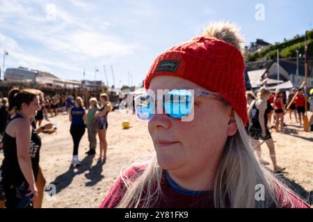 Eine Frau mit reflektierender Sonnenbrille, die beim Turnier der Cornish Pilot Gig Rowing im Newquay Harbour Harbor in New ansieht Stockfoto