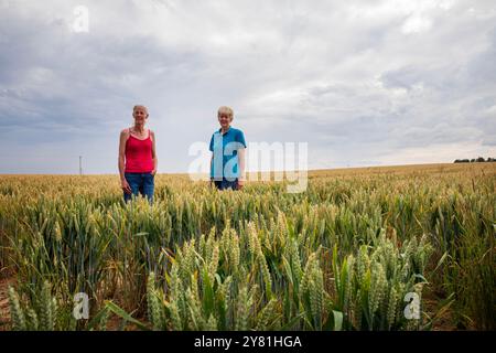 Nachbarn Donna Callaghan (rotes Hemd) und Jen Cooper, die neben der geplanten neuen National Grid Sub Station in Asserby leben. Auf dem Feld stehen, auf dem die Umspannstation gebaut werden kann. Der geplante Standort einer New National Grid Substation in Asserby nahe der Historic Town of Alford, Lincolnshire. Das Umspannwerk wird Teil eines neuen Netzes aus oberer und unterirdischer Stromleitung sein, das Strom vom Offshore-Windpark auf die Ostküste Englands hinauf und hinunter transportiert. Stockfoto