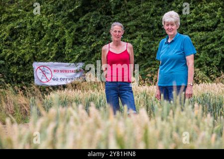 Nachbarn Donna Callaghan (rotes Hemd) und Jen Cooper, die neben der geplanten neuen National Grid Sub Station in Asserby leben. Auf dem Feld stehen, auf dem die Umspannstation gebaut werden kann. Der geplante Standort einer New National Grid Substation in Asserby nahe der Historic Town of Alford, Lincolnshire. Das Umspannwerk wird Teil eines neuen Netzes aus oberer und unterirdischer Stromleitung sein, das Strom vom Offshore-Windpark auf die Ostküste Englands hinauf und hinunter transportiert. Stockfoto