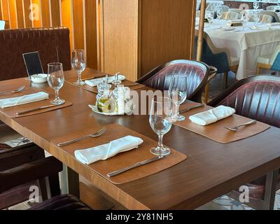 Gemütliches Restaurant mit elegant gedecktem Tisch, bereit für Gäste. Die Wärme der Holzakzente und grünen Pflanzen schaffen eine einladende Atmosphäre. Stockfoto