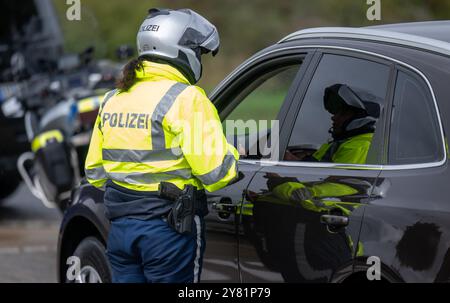 Chemnitz, Deutschland. Oktober 2024. Eine Polizistin kontrolliert im Rahmen eines bundesweiten Such- und Kontrolltages ein Auto auf der Raststätte Auerswalder Blick an der Autobahn 4 bei Chemnitz. Am Tag der Fahndung waren Kontrollpunkte in den jeweiligen Zuständigkeitsbereichen der Polizeistationen der Chemnitzer Polizeidienststelle und auf der A4 besetzt. Gleichzeitig wurden mobile Kontrollen durchgeführt. Unterstützung leisteten Bundespolizisten und Zollbeamte. Quelle: Hendrik Schmidt/dpa/Alamy Live News Stockfoto