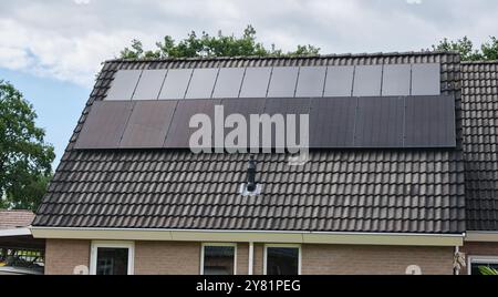 Zwei große Solarpaneele, die auf dem Dach eines Wohnhauses installiert sind, zeigen den Fortschritt erneuerbarer Energien im Laufe der Jahre im modernen Leben. Stockfoto