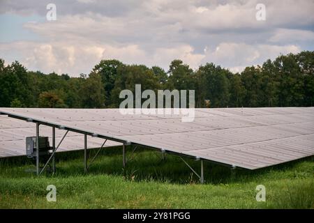Ein großer Solarpark mit Reihen von Photovoltaik-Panels, neben einer Autobahn, in einer ländlichen Gegend mit Bäumen und blauem Himmel. Erzeugung erneuerbarer Energien Stockfoto
