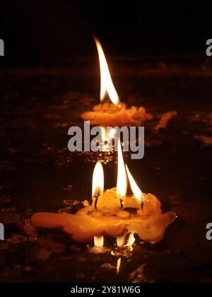 Nahaufnahme brennendes gelbes Kerzenlicht auf Sandkasten in dunklem Hintergrund, Verdienst, Glauben oder Glauben, Gebet in Respekt, friedliches Konzept, Religion Stockfoto