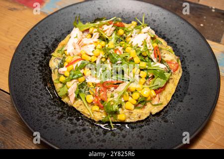 Ein Teller mit köstlichem Lachs und Zuckermais Frittata, serviert mit einem Frühlingszwiebeldressing auf einem schwarzen Teller auf einem hölzernen Küchentisch Stockfoto