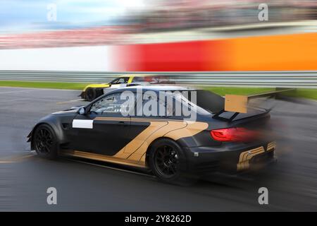 Zwei Rennwagen fahren mit hoher Geschwindigkeit auf einer Geschwindigkeitsstrecke mit Bewegungsunschärfe Stockfoto