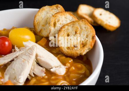 Geröstete Cracker, Hühnchen, Tomaten mit Suppe in einer weißen Schüssel horizontal Stockfoto