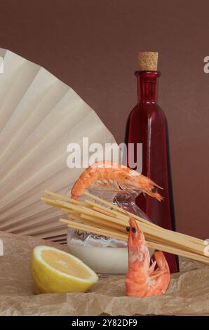 Garnelen mit Zutaten für Garnelenspaghetti: Eine rote Ölflasche, eine halbe Zitrone und eine Sahne in einer kleinen, klaren Flasche, für einen lebendigen, frischen Kompott Stockfoto