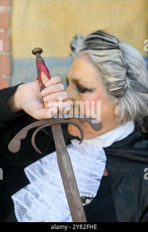 Die ältere Richterin hält ein antikes Schwert in der Hand und posiert für ein Porträt. Sie trägt einen schwarzen Justizmantel mit einem weißen Spitzenjabot Stockfoto