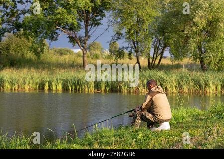 Angelrute See Ein Fischer auf dem See fängt im Sommer Fische vom Ufer Stockfoto