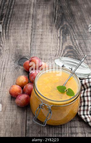 Hausgemachte Pflaumenmarmelade im Glasgefäß auf Holztisch Stockfoto