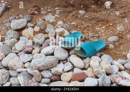 Eine stylische, hellblaue Sandale liegt auf einem Steinhaufen Stockfoto