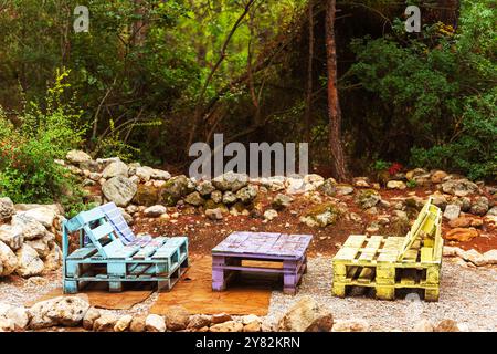 Zwei farbenfrohe Stühle und ein Tisch, der aus Holzpaletten hergestellt wird Stockfoto