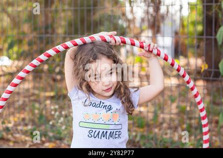 Goiania, Goias, Brasilien – Setembro 20, 2024: Ein kleines Mädchen, das draußen mit einem Hula Hoop spielt. Stockfoto