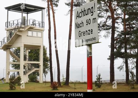 Geisa, Deutschland. Oktober 2024. „Achtung! Nach 50 m Grenze - Bundesgrenzschutz“ steht auf einem Schild neben einem Aussichtsturm auf dem Gelände der Gedenkstätte „Point Alpha“ der Deutschen Einheit. Der Tag der Deutschen Einheit wird in Deutschland am 3. Oktober gefeiert. Quelle: Bodo Schackow/dpa/Alamy Live News Stockfoto