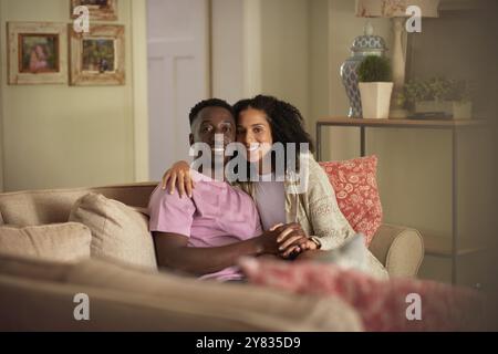 Porträt eines liebevollen jungen multirassischen Paares, das zu Hause auf dem Sofa sitzt Stockfoto