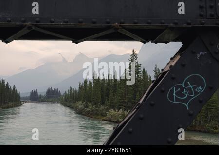 Eiserne Brücke über den Bow River mit Bergen in rauchiger Atmosphäre bei Waldbränden in Canmore, Alberta, Kanadischen Rocky Mountains Stockfoto