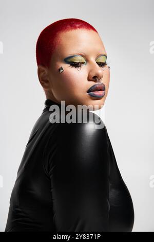 Diese kühne junge Frau mit auffälligen rosa Haaren und einzigartigem Make-up drückt ihre lebendige Persönlichkeit in einem Studio aus. Stockfoto