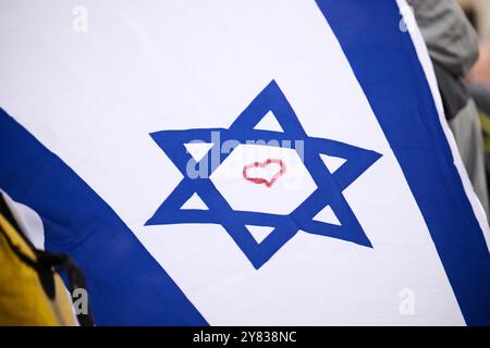 Berlin, Deutschland. Oktober 2024. Ein rotes Herz ist in den Davidstern auf einer Isrealflagge gemalt, während die Flagge auf der Solidaritätskundgebung „Deutschland an Israels Seite – am Israel Chai!“ fliegt. Am Brandenburger Tor. Annette Riedl/dpa/Alamy Live News Stockfoto