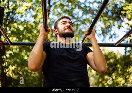 Sportmann dehnt sich im Herbst im Park aus und macht Übungen. Gutaussehender Mann macht Dehnungsübungen im Herbstpark. Sonnenuntergang im Park mit Bäumen und grünem Gras Stockfoto