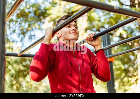 Sportmann dehnt sich im Herbst im Park aus und macht Übungen. Gutaussehender Mann macht Dehnungsübungen im Herbstpark. Sonnenuntergang im Park mit Bäumen und grünem Gras Stockfoto