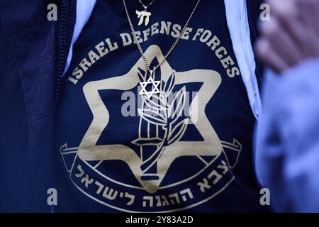 Berlin, Deutschland. Oktober 2024. "Israel Defense Forces" steht auf dem Pullover einer Frau, die eine Star of David Halskette trägt, während sie an der Solidaritätskundgebung "Deutschland an der Seite Israels - am Israel Chai!" teilnimmt. Am Brandenburger Tor. Annette Riedl/dpa/Alamy Live News Stockfoto