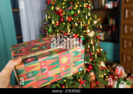 Viele Kisten mit Weihnachtsgeschenken in umweltfreundlichen Bastelpapierverpackungen und Garnen auf dem Boden unter dem Weihnachtsbaum Stockfoto