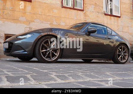 Brasov, Rumänien - 18. August 2024: Schwarzes Auto Mazda MX-5 parkt auf einer Kopfsteinpflasterstraße in einem alten Haus im historischen Zentrum der Stadt Stockfoto