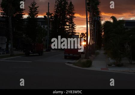 Horizontaler Blick auf Palmen in Richtung St. Pete Beach, FL in Richtung Golf von Mexiko. Nahe Sonnenuntergang am späten Nachmittag. Goldene bunte Wolken Stockfoto