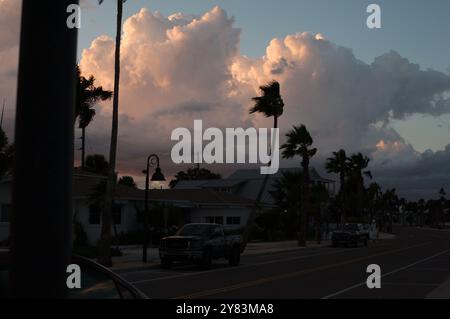 Horizontaler Blick auf Palmen in Richtung St. Pete Beach, FL in Richtung Golf von Mexiko. Nahe Sonnenuntergang am späten Nachmittag. Goldene bunte Wolken Stockfoto