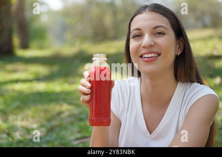 Brasilianische junge Frau, die im Freien roten Rüben-Entgiftungssaft hält. Blick auf die Kamera. Kopierbereich. Stockfoto