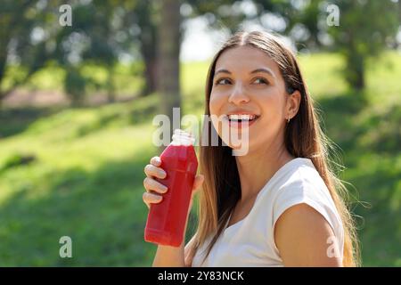 Gesundes Fitness-Mädchen trinkt roten Smoothie Entgiftungssaft mit Rote-Bete-Orangen-Karotte im Stadtpark Stockfoto