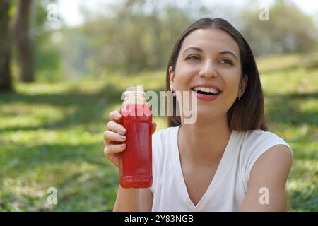 Wunderschönes brasilianisches Mädchen, das im Freien roten Rüben-Entgiftungssaft hält Stockfoto