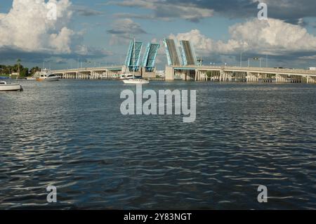 Blick von der Intercoastal in Richtung blau geöffneter Corey Causeway Zugbrücke. Zwei Segelboote in der Mitte und andere Boote, die unter der Brücke fahren. Geschwollenes Stockfoto