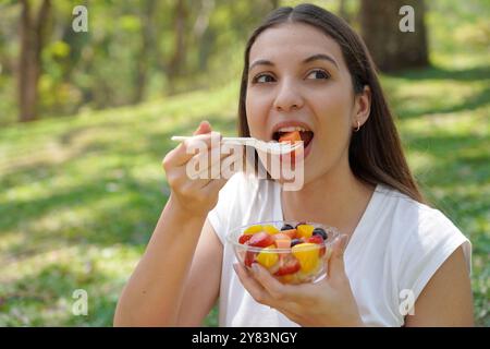 Eine junge Frau isst einen Obstsalat im Park. Gesundes und Wellness Lifestyle Konzept. Stockfoto