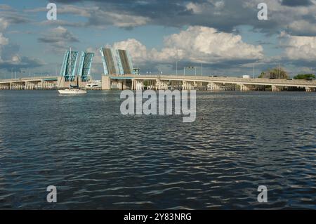 Blick von der Intercoastal in Richtung blau geöffneter Corey Causeway Zugbrücke. Zwei Segelboote in der Mitte und andere Boote, die unter der Brücke fahren. Geschwollenes Stockfoto