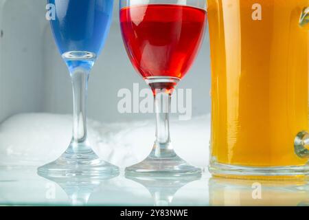 Bunte Cocktails in Gläsern, auf Glastisch und Eiskühler Hintergrund Stockfoto