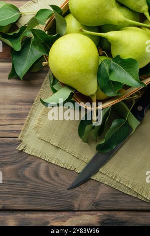 Gartenarbeit. Herbsternte. Grüne reife Birnen in einer Schachtel auf dunklem Hintergrund. Birne aus dem Garten. Köstliche Birnen aus der Nähe. Draufsicht, flach. Copyspa Stockfoto